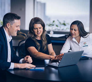 Three consulting professionals reviewing data on a laptop.