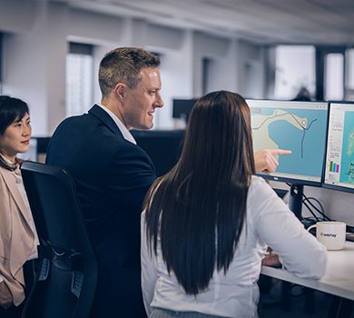 Three engineers standing in front of monitors working with simulation software and analytic tools.