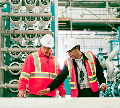 Two men wearing PPE working inside a power station.