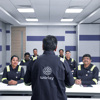 Engineer standing at the front of the room talking to a group of several engineers.